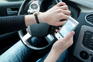A young female's hand holding a smartphone while driving.